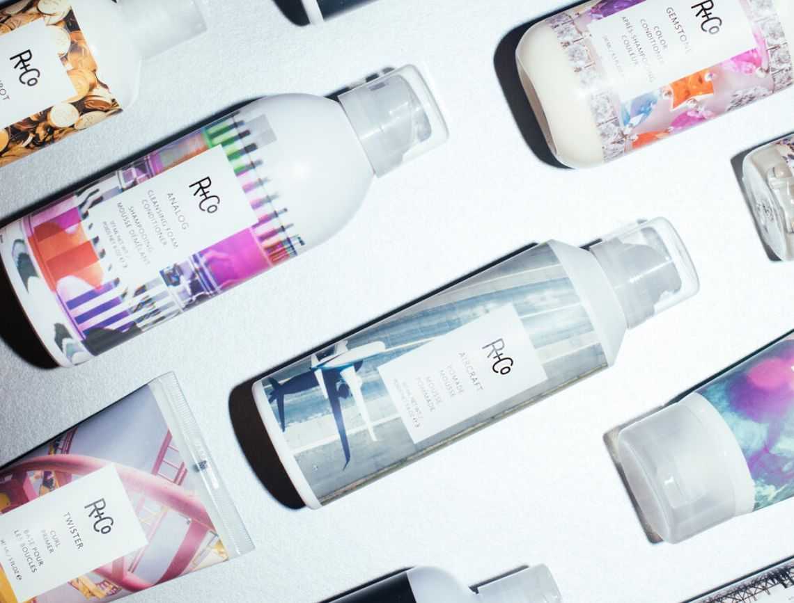 R+Co haircare products arranged on a flat surface, featuring colorful label designs.