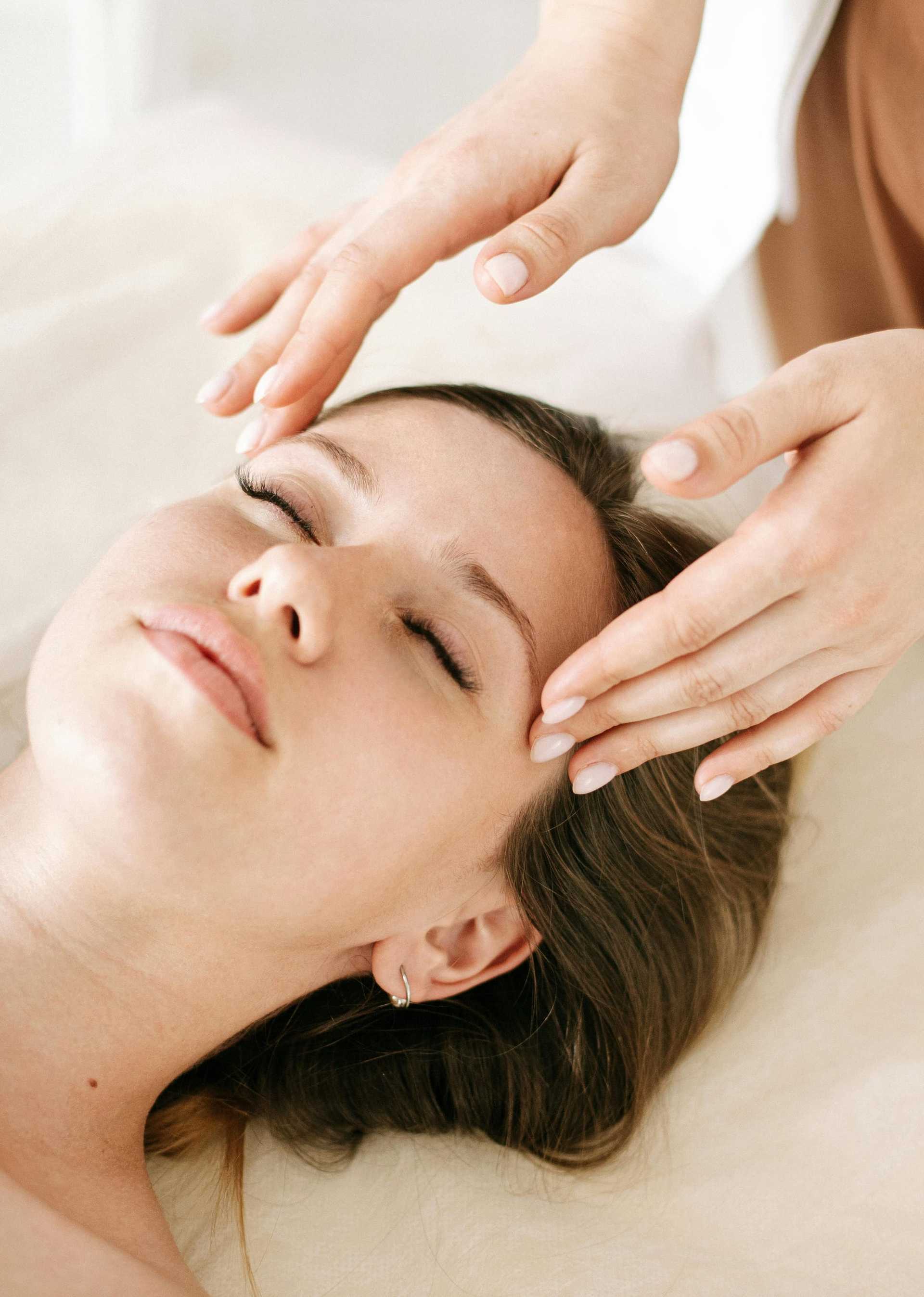 Facial massage therapy on a relaxed woman with eyes closed.