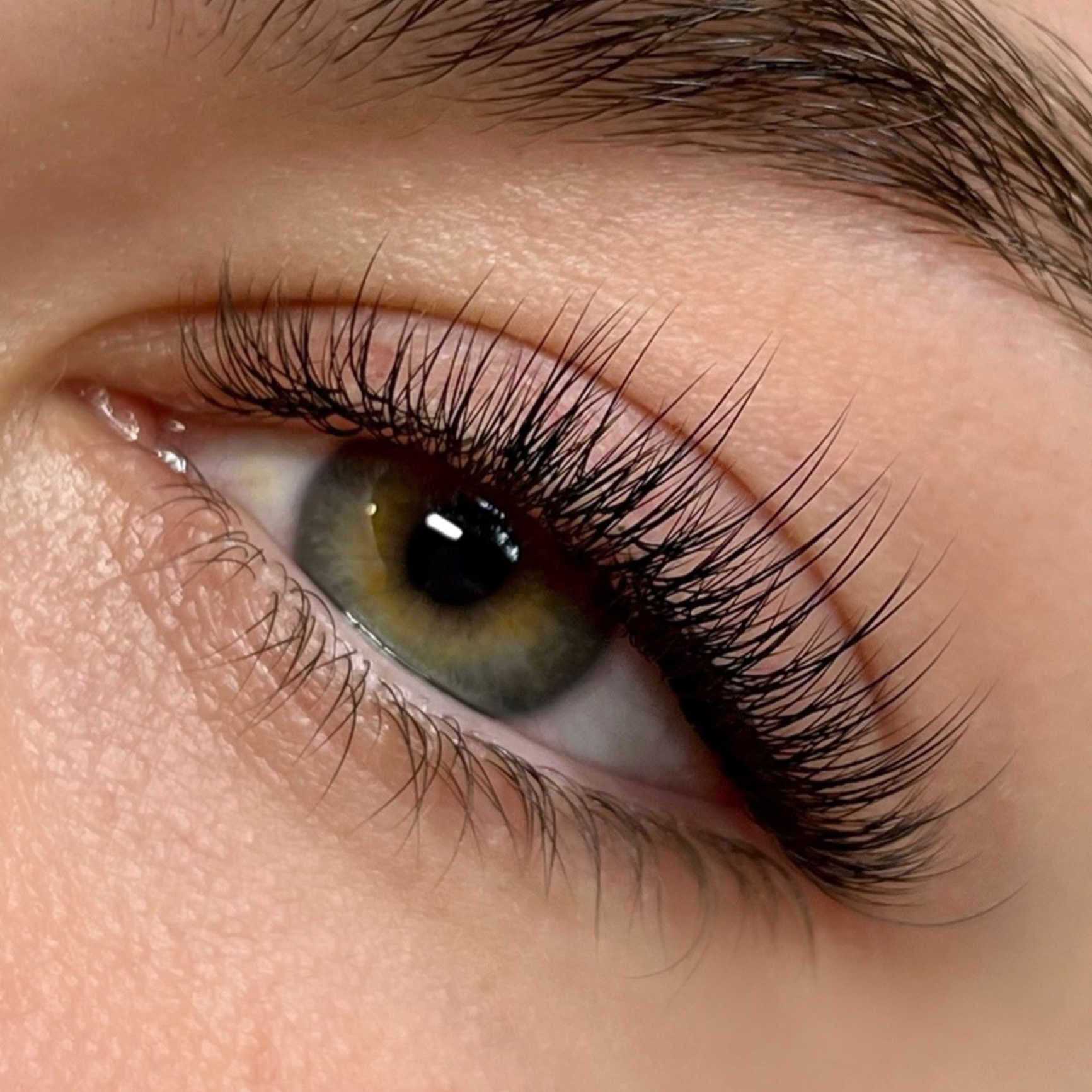 Close-up of a green eye with long, thick eyelashes.