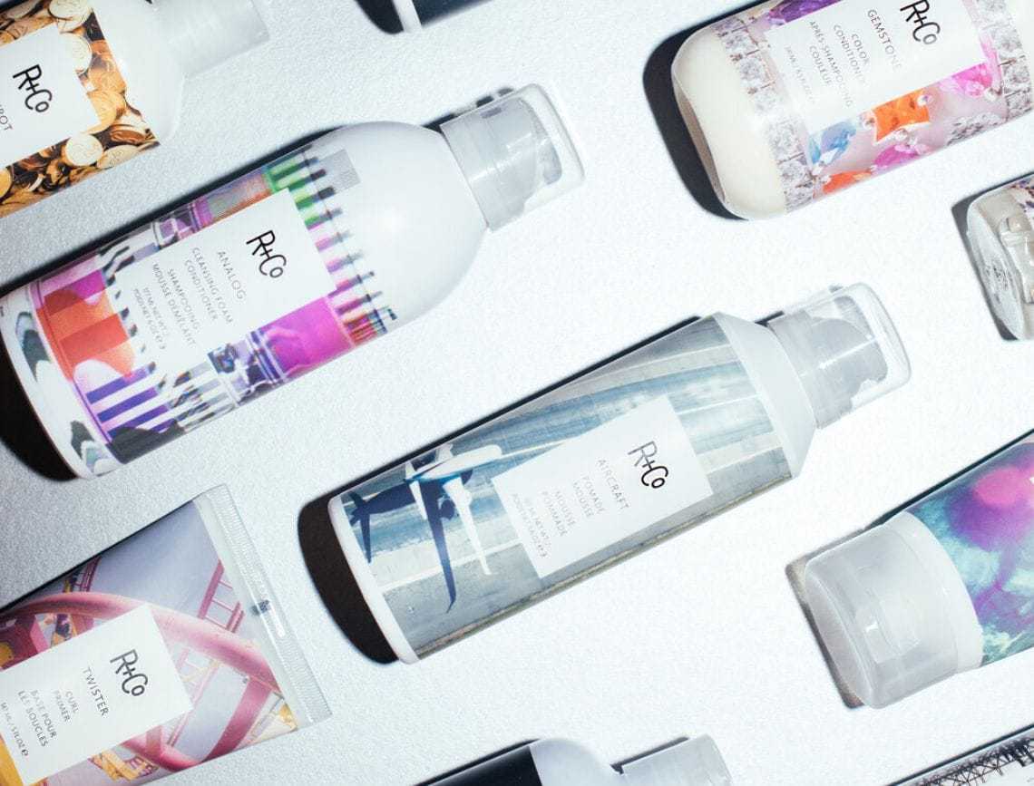 R+Co haircare products arranged on a flat surface, featuring colorful label designs.